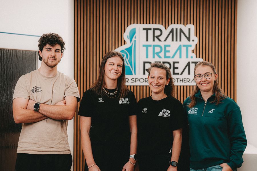 Das Team der Sportphysiotherapie Färber vor dem Logo Train. Treat. Repeat.